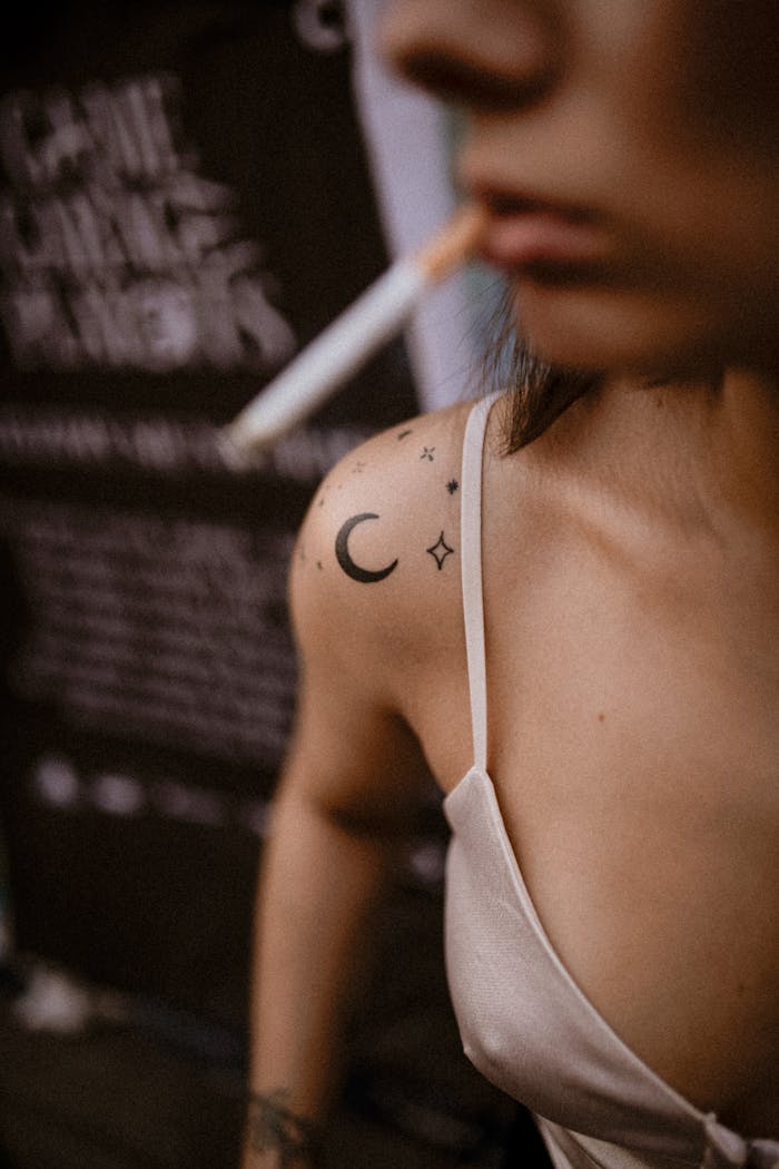 Artistic close-up of a tattooed woman smoking, highlighting urban lifestyle.