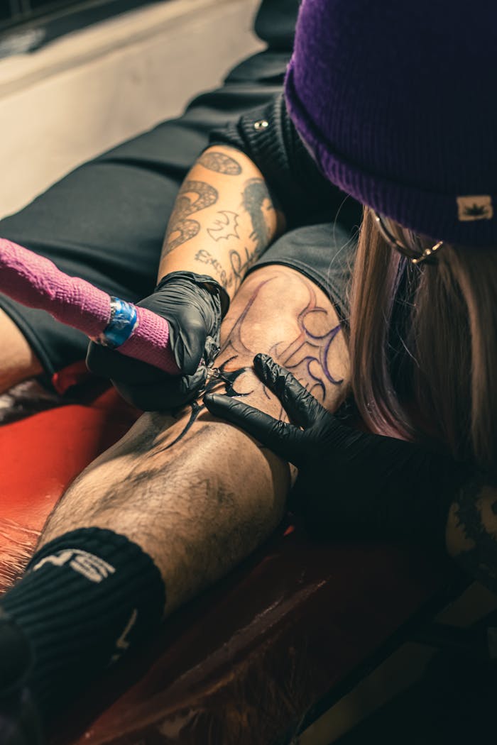Detailed view of a tattoo artist working on a client's leg in a studio, Ciudad de México.