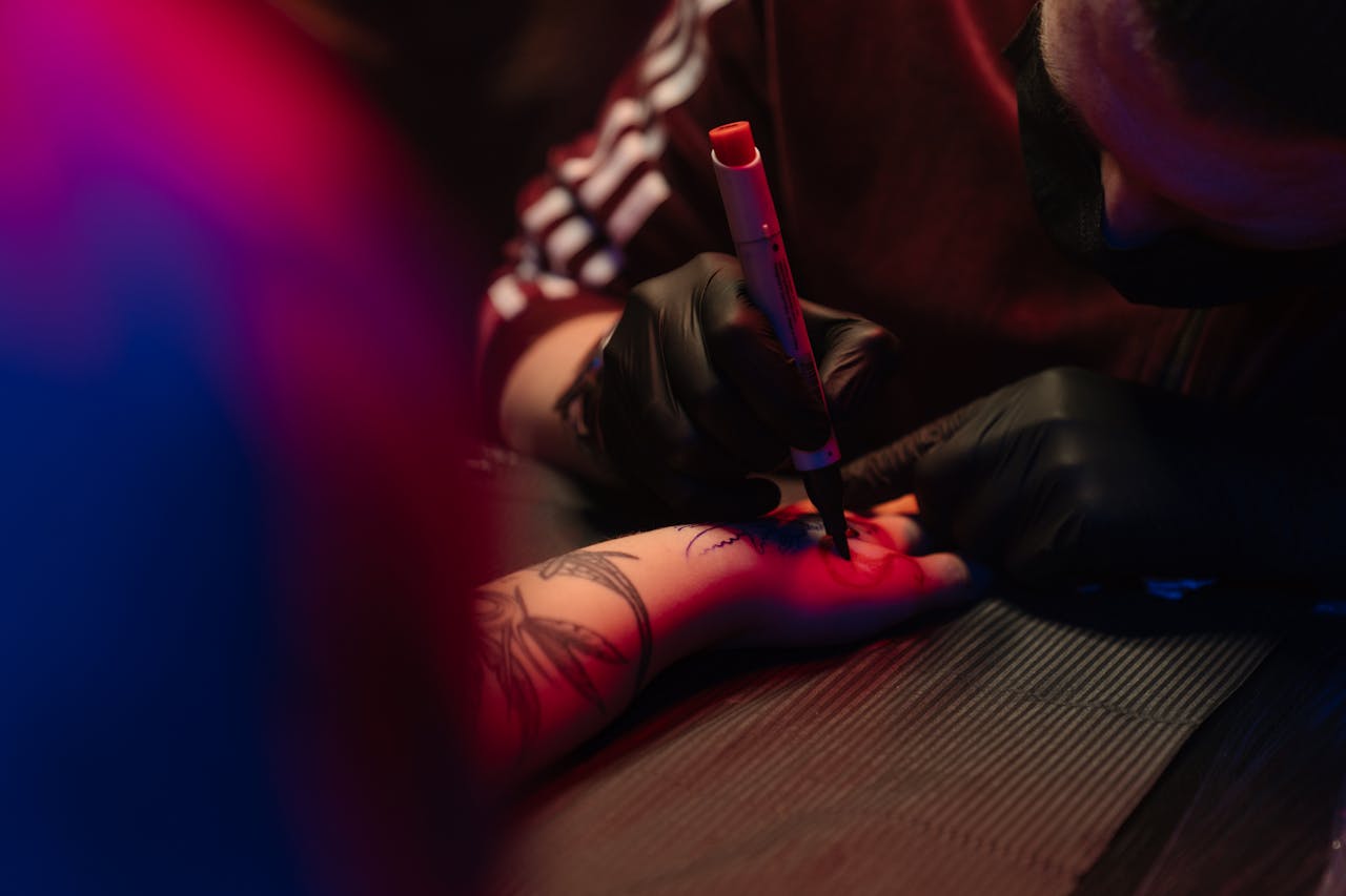 Tattoo artist skillfully inking a client's arm under neon lights. Creative process in action.